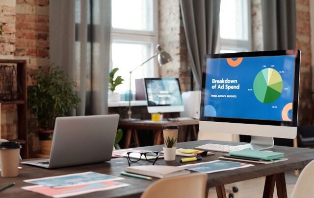 A modern office workspace featuring computers, charts, and office supplies for a productive environment.